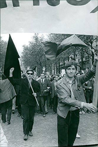 Foto vintage de pessoas protestando e segurando bandeiras na rua em Paris.